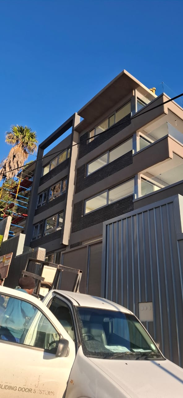 Angled view showing flush glass panels on the upper levels of the Sea Point building.