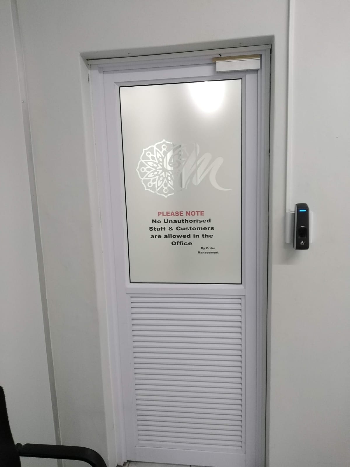 Half-glass, half-aluminium self-closing door leading to staff area at Mubarak Foods, Lansdowne.