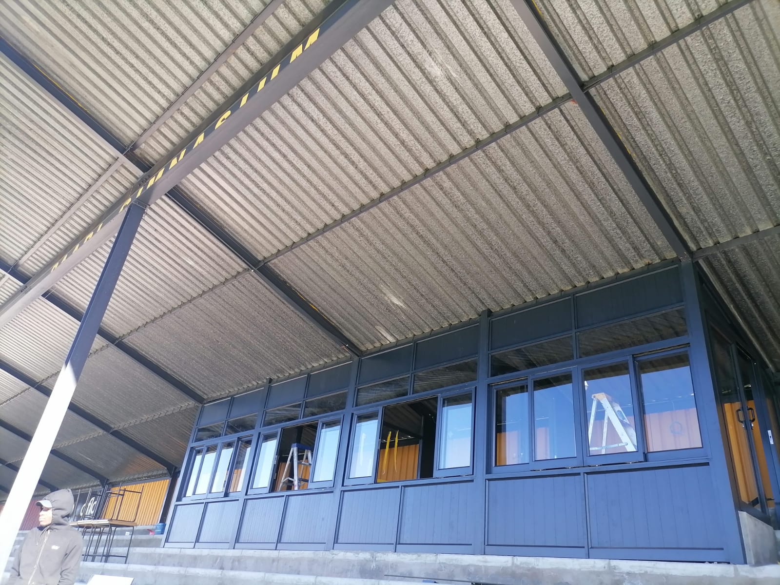 Distant view of Paarl Gymnasium High School stadium benches with aluminium sliding windows in the background.