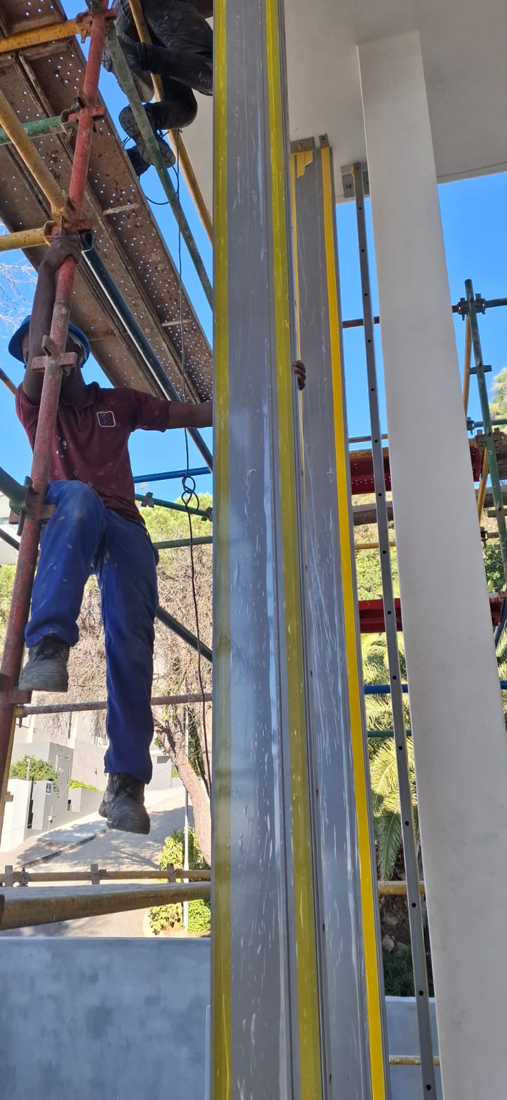 Technicians aligning and securing glass panels to the aluminium framing system in Sea Point.