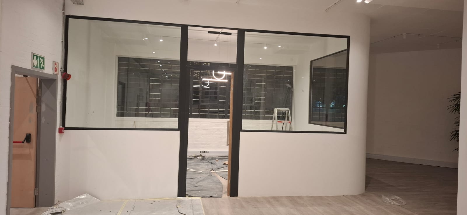Wide-angle interior of Walden project highlighting full-height black aluminium framed shopfronts and reflective glass panels.