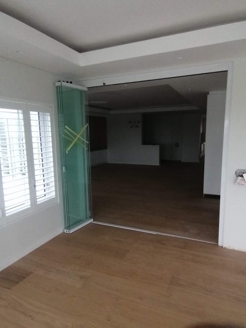 Frameless sliding glass doors fully opened and stacked along the side wall.