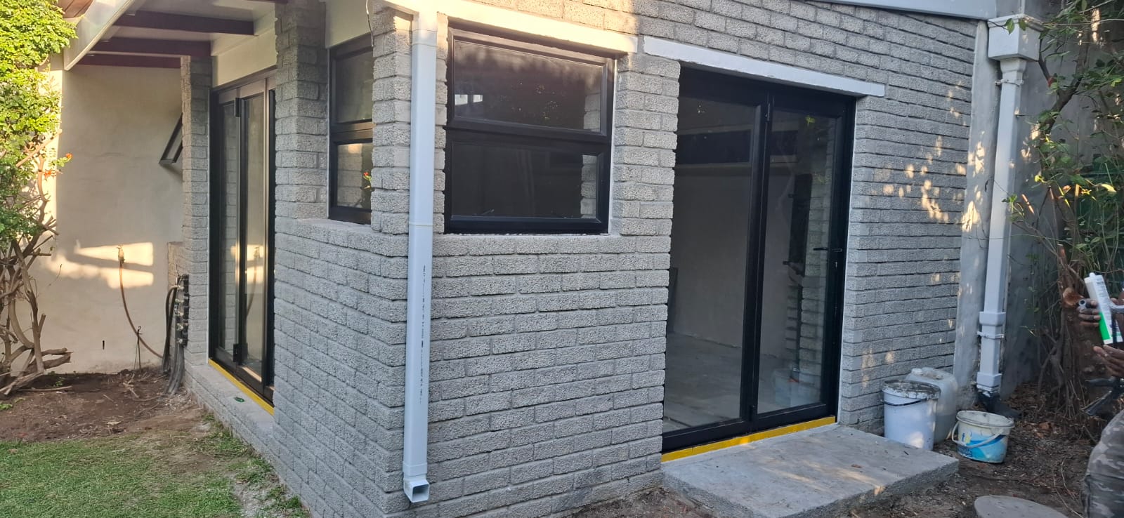 Corner view of a house in Sweet Valley, Bergvliet, showing aluminium sliding doors and a casement window on two adjoining walls.