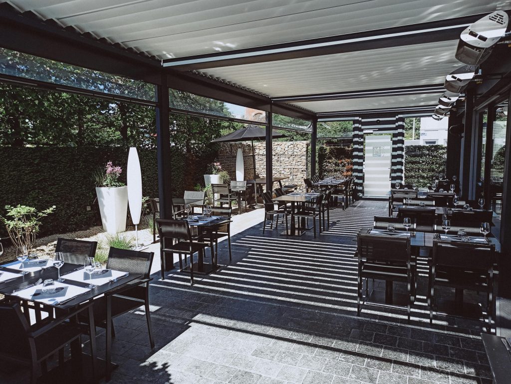 Spacious outdoor dining area with tables, chairs, and ambient lighting.